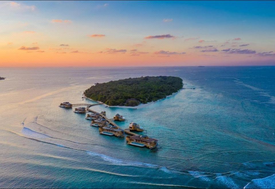 Vista aérea do Soneva Fushi com villas sobre a água e reef nas Maldivas